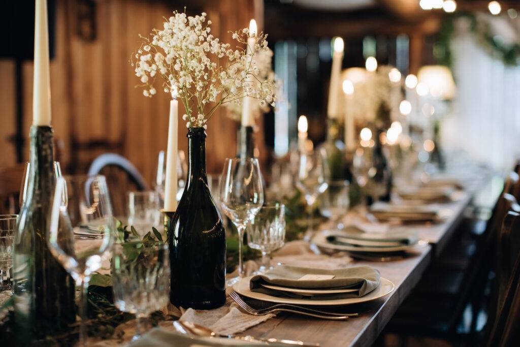 Festlich gedeckter Tisch mit wunderschöner Tischdeko für eine Hochzeit im rustikalen Stil, Dekoideen mit Kerzen und Weinflaschen.