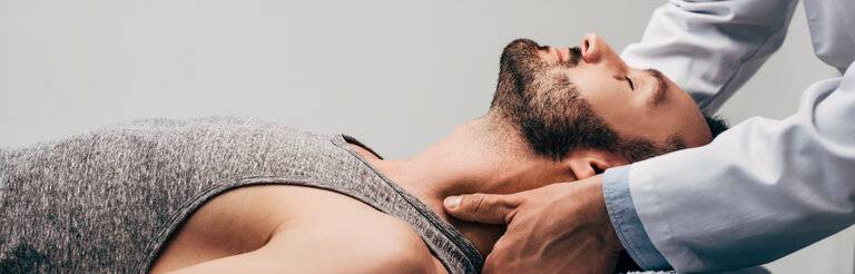Panoramaaufnahme eines Chiropraktikers, der den Nacken eines Mannes auf einer grauen Fläche massiert