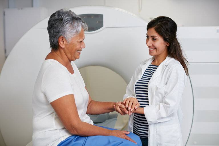 CT-Scan, Ärztin hält Hände des Patienten im Krankenhaus vor dem Scannen in der Maschine. MRT, Komfort und glücklich medizinische Fachkraft mit älteren weiblichen Person vor Radiologie-Test für die Gesundheitsversorgung