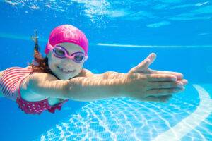 kleines Mädchen schwimmt geschickt unter Wasser im Pool