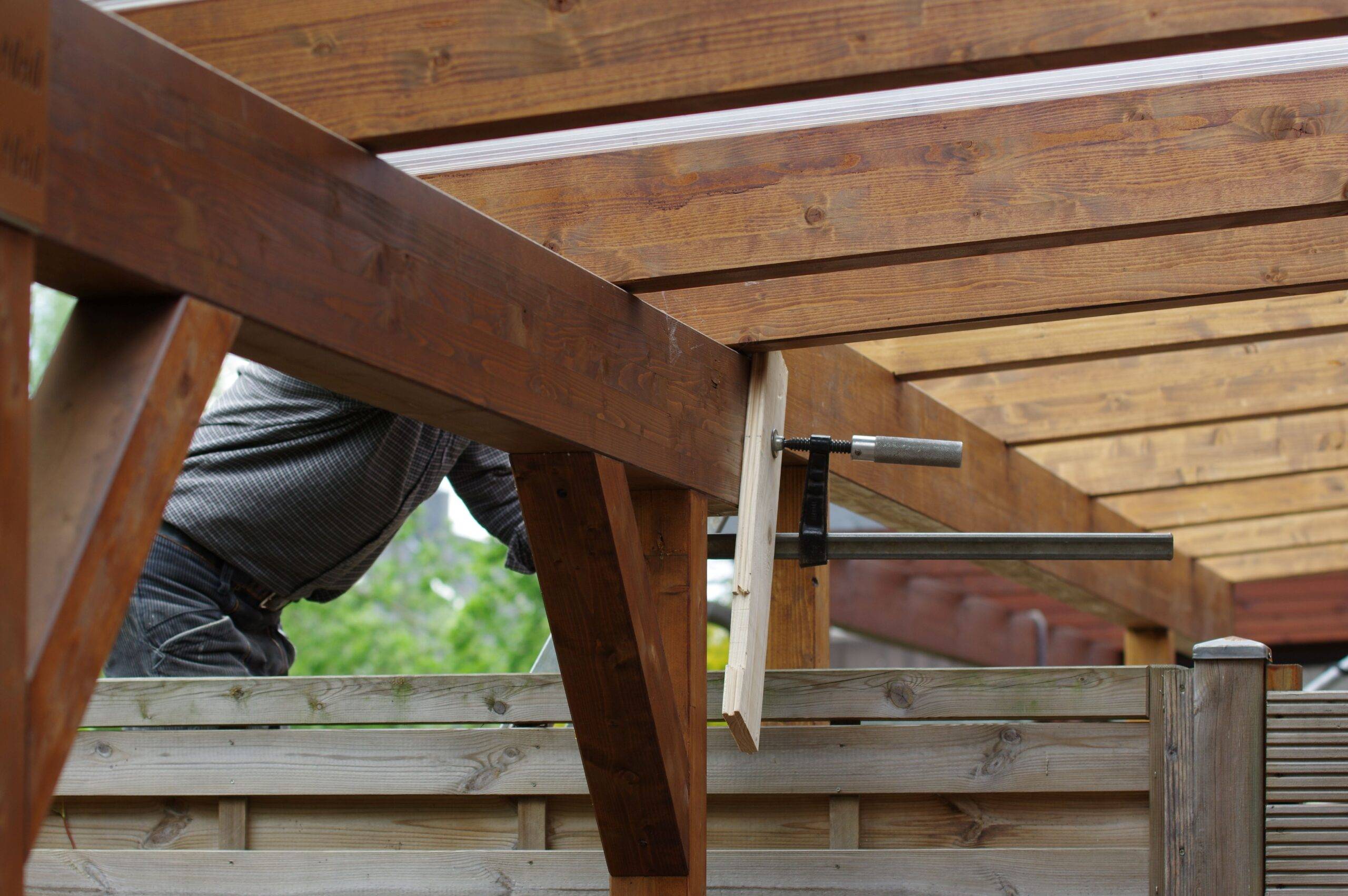 Montage einer Terrassenüberdachung Köln durch lokalen Handwerker mit Zwinge und Holzkonstruktion im Garten