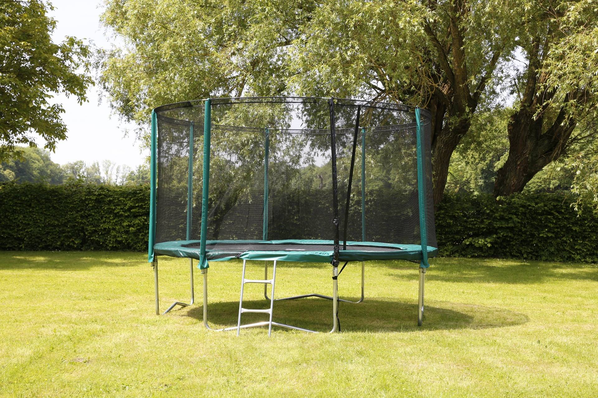 Großes Trampolin mit umlaufendem Netz auf Wiese | Pools